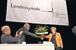 Gratulation in Corona-Zeiten: Synodalpräsident Hermann Lorenz überreicht Blumen, Matthias Schwarz hält die Szene fest. Foto: Landry