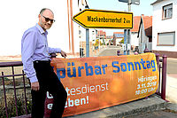 In der Ortsmitte von Höringen an der Hauptstraße: Gemeindepfarrer Karsten Scholl mit dem Einladungstransparent. Foto: Löffel