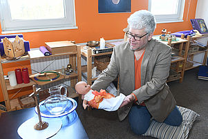 Lebendige Erzählung mit Babypuppe: Pfarrer Uwe Schutte widmet sich mit Godly Play dem Thema Taufe. Foto: Stepan