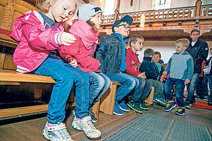 In der allerersten Reihe im Kirchenschiff: Erstes Probesitzen auf den Minibänken beim Kindergottesdienst. Foto: Hoffmann