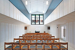 Moderner Kirchenraum mit variabler Bestuhlung: Das Glastriptychon des Künstlers Eugen Keller im Mittelpunkt. Foto: Paustian
