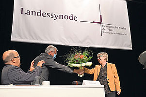 Gratulation in Corona-Zeiten: Synodalpräsident Hermann Lorenz überreicht Blumen, Matthias Schwarz hält die Szene fest. Foto: Landry